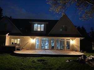 Rear deck lit up at dusk behind a lakeside home