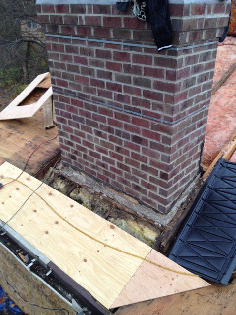 Chimney with rotted roof deck exposed before repair