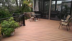 Composite deck floor with railing and a screened porch behind it
