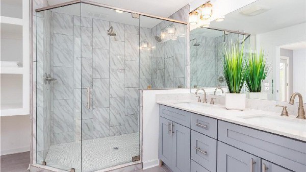 Marble tile walk-in shower with frameless glass and gray double vanity