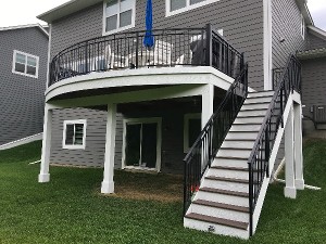 Curved elevated deck with black metal railing and open stair run